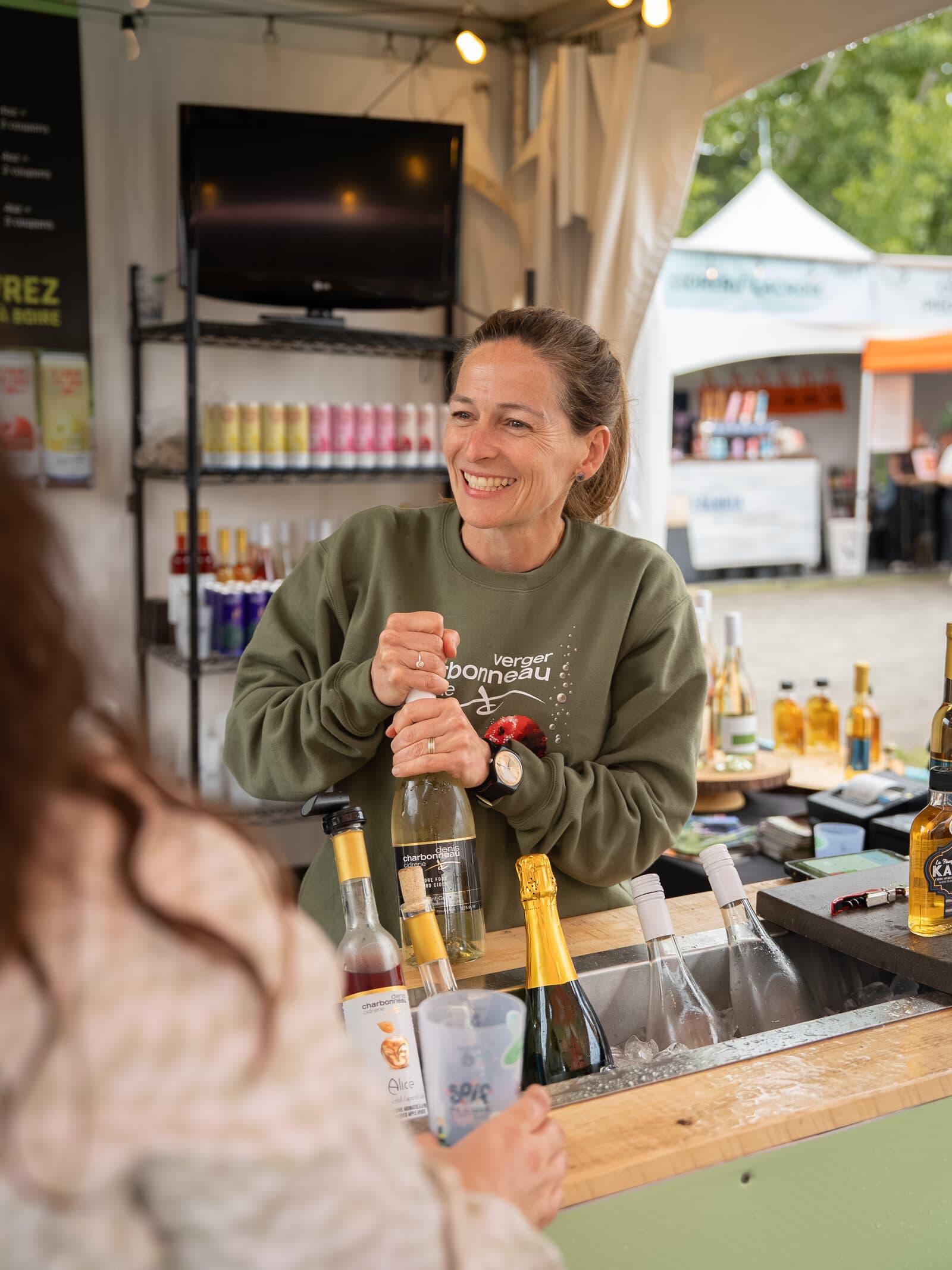 Mélanie Charbonneau au caveau de dégustation, entourée de bouteilles de cidre